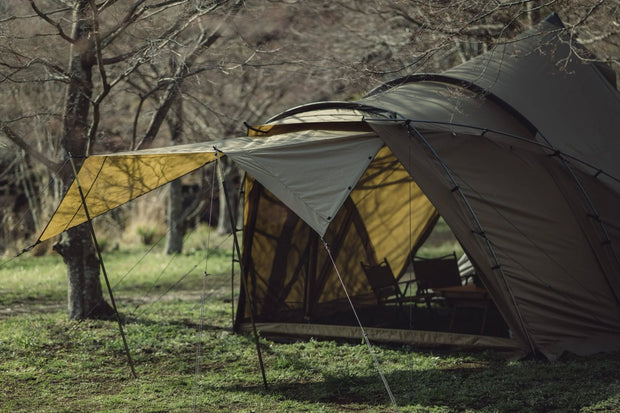 Zane Arts LoLo pitched among trees with its front awning open.